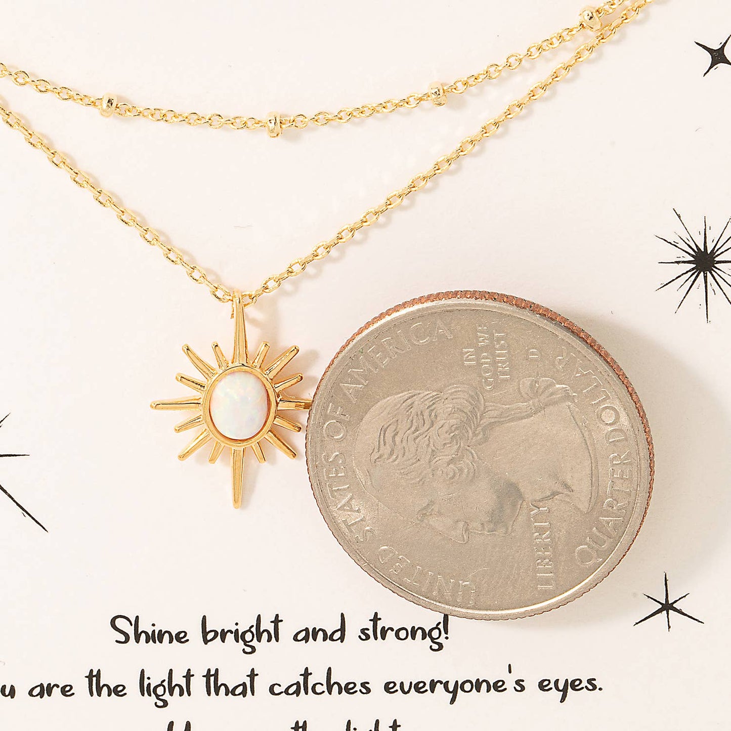 Gold double-layer necklace featuring a radiant sun pendant with a white opal center, displayed on a decorative card with the word 'Sparkle' at the top. The card includes an inspirational message and celestial star graphics, emphasizing the piece's uplifting and elegant design. Made with 18K gold plating, perfect for gifting or adding a luminous touch to any outfit.