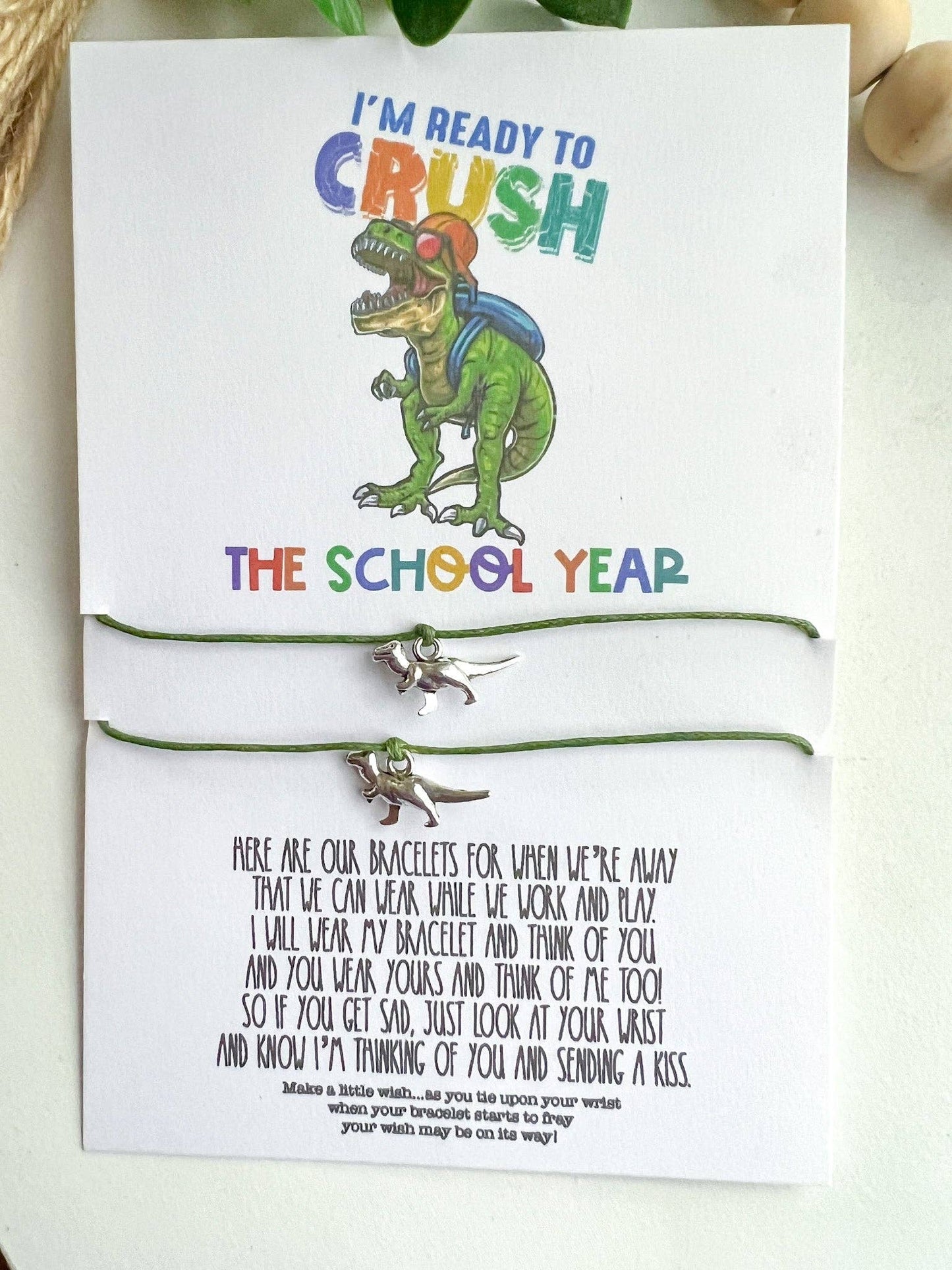 Children’s dinosaur-themed bracelet set on a card with the text "I'm Ready to Crush the School Year" featuring a fun T-rex wearing a backpack and headphones. The card includes an inspiring poem, making this accessory a perfect back-to-school gift for kids.