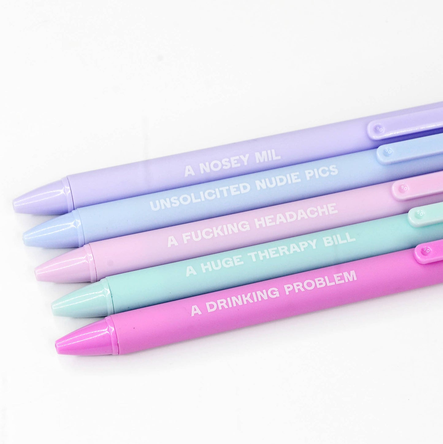 Pastel-toned pen set with cheeky phrases such as 'A Nosey MIL' and 'A Huge Therapy Bill,' packaged in a mint green box. A playful and relatable gift for those with a sense of humor.