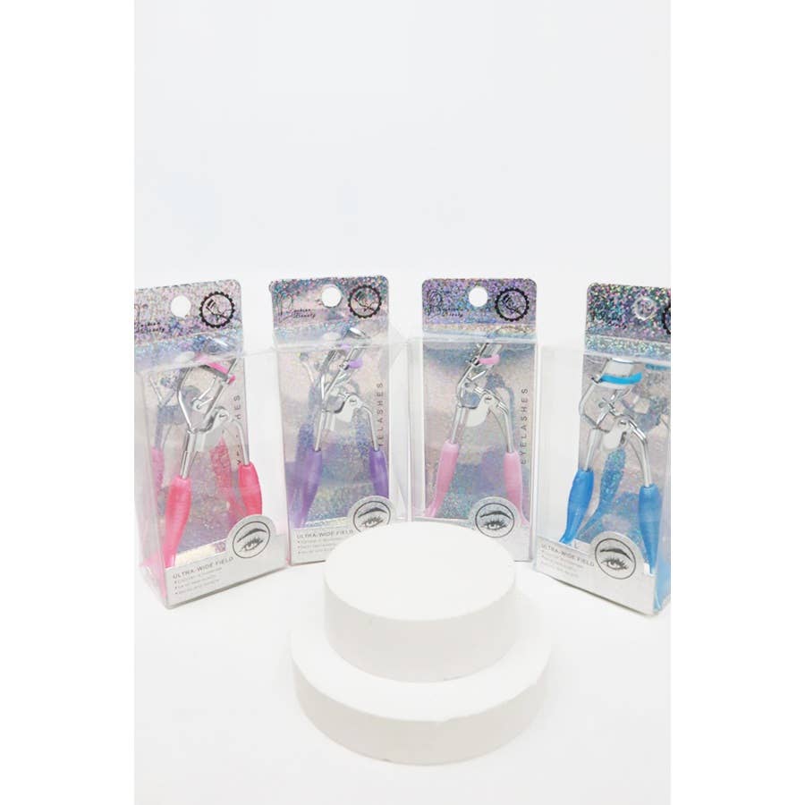A set of four eyelash curlers displayed in glittery, holographic packaging. Each curler features a chrome metal frame with colorful silicone handles and matching curling pads in pastel shades of pink, purple, magenta, and blue. The packaging highlights their "Ultra-Wide Field" design, emphasizing functionality and style. Perfect for beauty enthusiasts seeking a pop of color in their makeup tools.