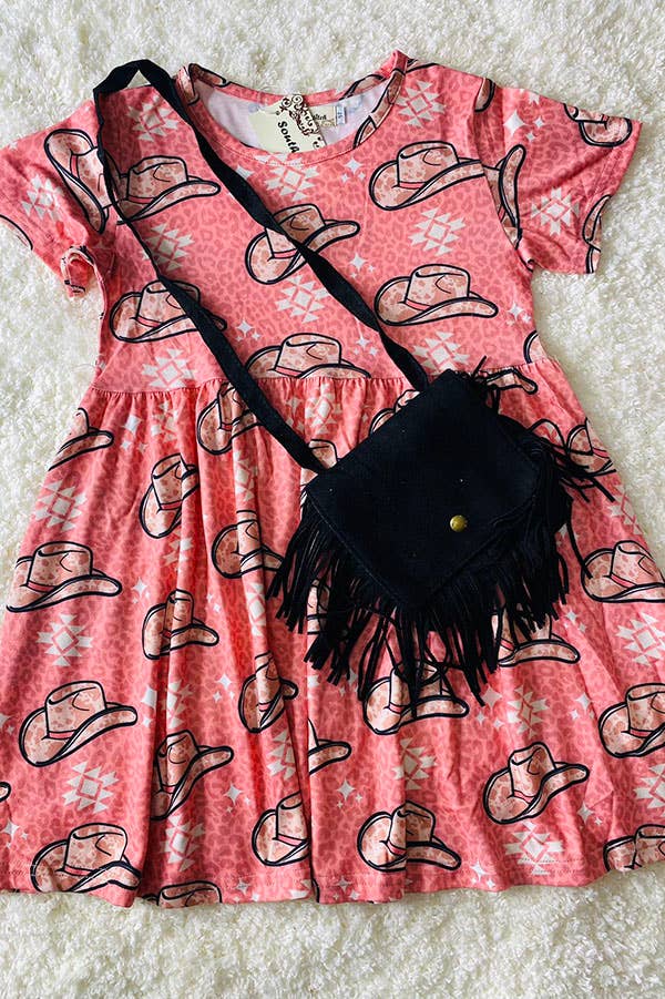 Pink short-sleeve dress with a Western-themed design featuring cowboy hats and geometric patterns, paired with a black fringe crossbody bag for a playful, country-inspired outfit. Displayed on a soft white textured background.