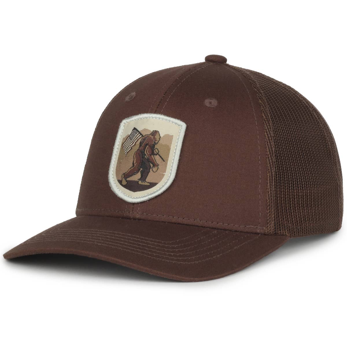 Brown trucker cap with a curved bill and mesh back, featuring a patch on the front depicting Bigfoot carrying an American flag and a bow. The design combines outdoor and patriotic themes, perfect for casual or adventure wear.