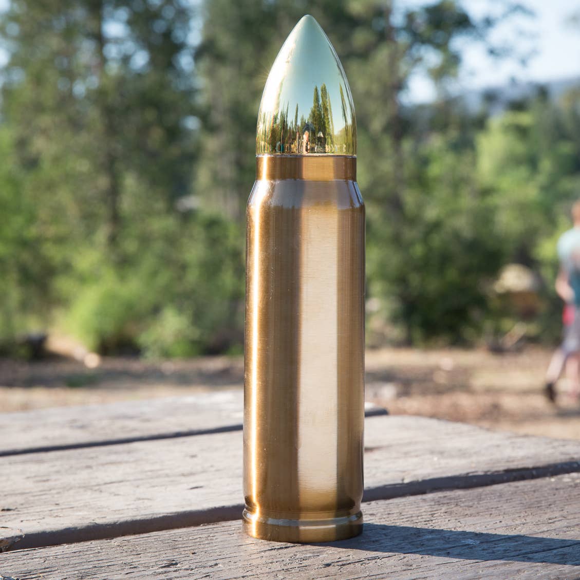 A disassembled view of the bullet-shaped thermos on a white background. The thermos's main body is metallic gold, while the detachable tip, which doubles as a lid, is a polished gold color. The interior features a shiny stainless steel finish.