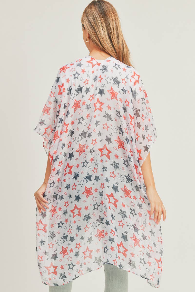A woman modeling a lightweight, sheer kimono with a patriotic star pattern in red, navy blue, and white. The open-front kimono features a flowing, loose-fit design that drapes effortlessly over a white ribbed top and light-wash jeans. Perfect for layering during casual outings or holiday events, offering a stylish yet breezy look.