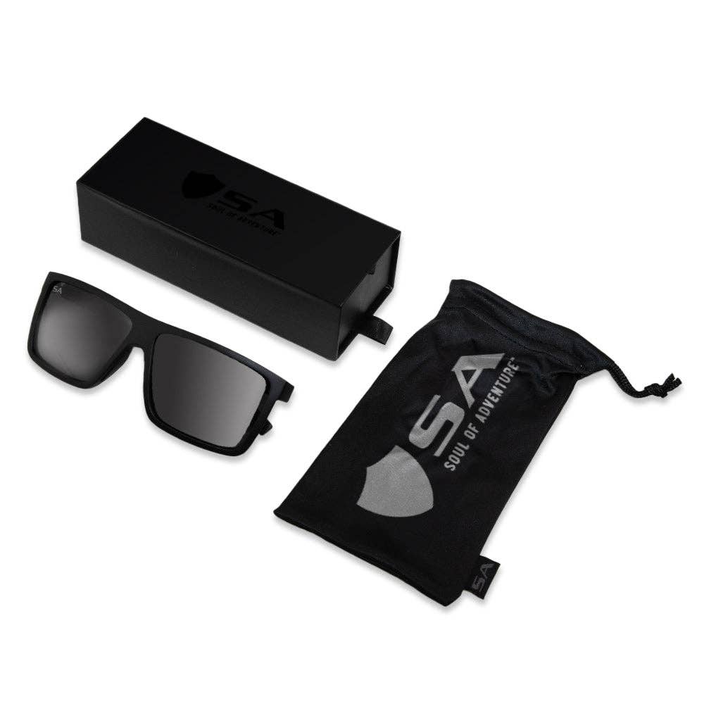 A pair of black rectangular sunglasses with dark tinted lenses, featuring a minimalist design and subtle detailing on the arms, shown against a white background.