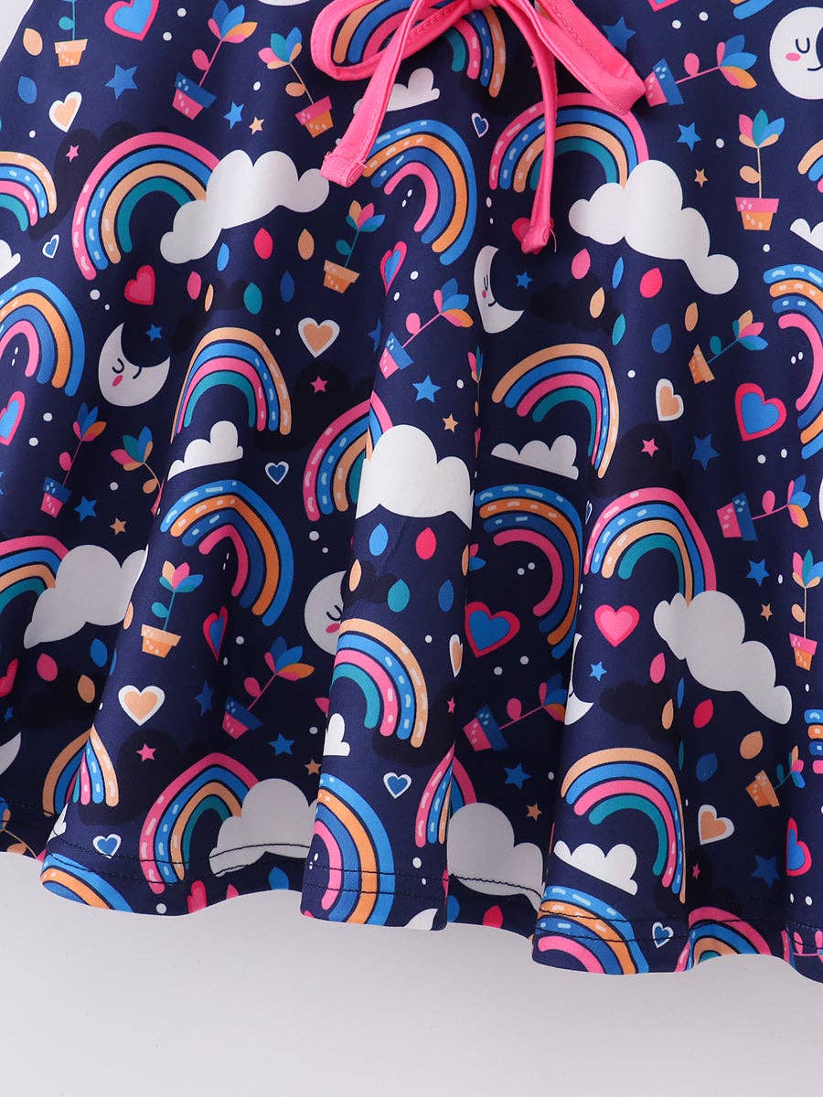 A colorful, sleeveless girls' dress featuring a playful, navy blue background adorned with vibrant prints of rainbows, clouds, stars, hearts, potted plants, and crescent moons with smiling faces. The dress has flutter sleeves, a bright pink collar, and a matching pink drawstring detail at the waist for a cinched fit. The whimsical pattern and cheerful colors make it ideal for casual wear or fun occasions.