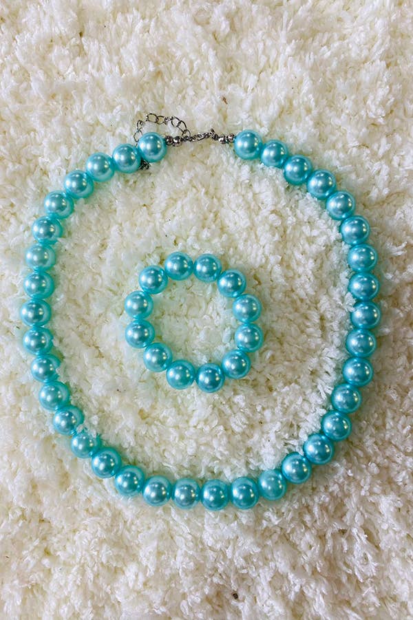 Charming turquoise pearl jewelry set featuring a necklace and matching bracelet. The necklace includes an adjustable clasp for a comfortable fit, while the elastic bracelet ensures easy wear. Perfect for adding an elegant pop of color to any outfit. Displayed on a soft, textured white background for a luxurious feel.
