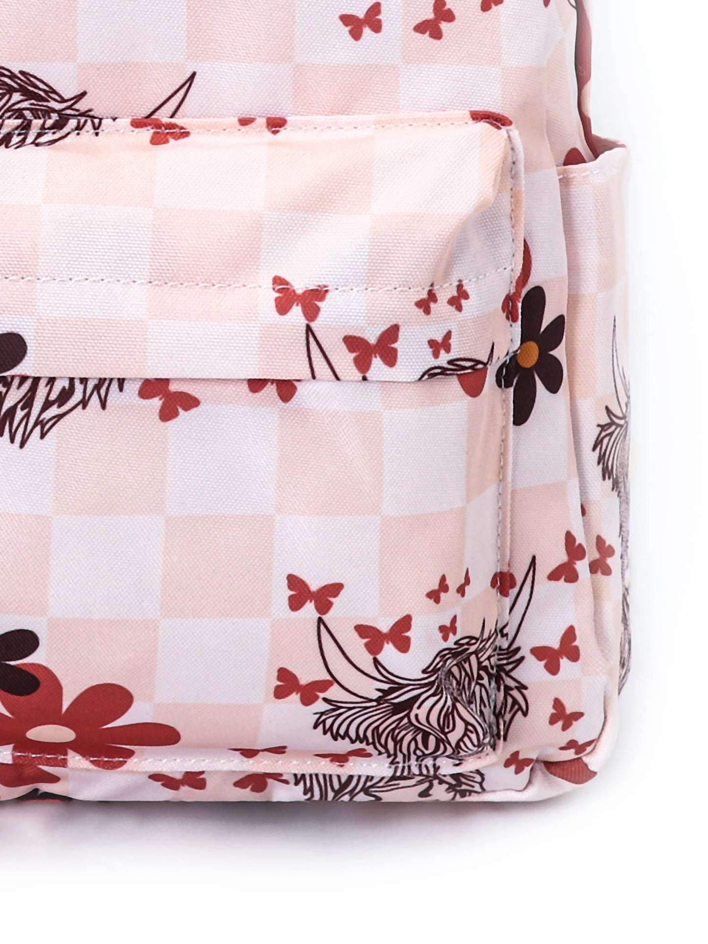 close up of the backpack with a pink and cream checkered pattern, featuring a playful design of illustrated highland cows, red and black flowers, and small red butterflies.
