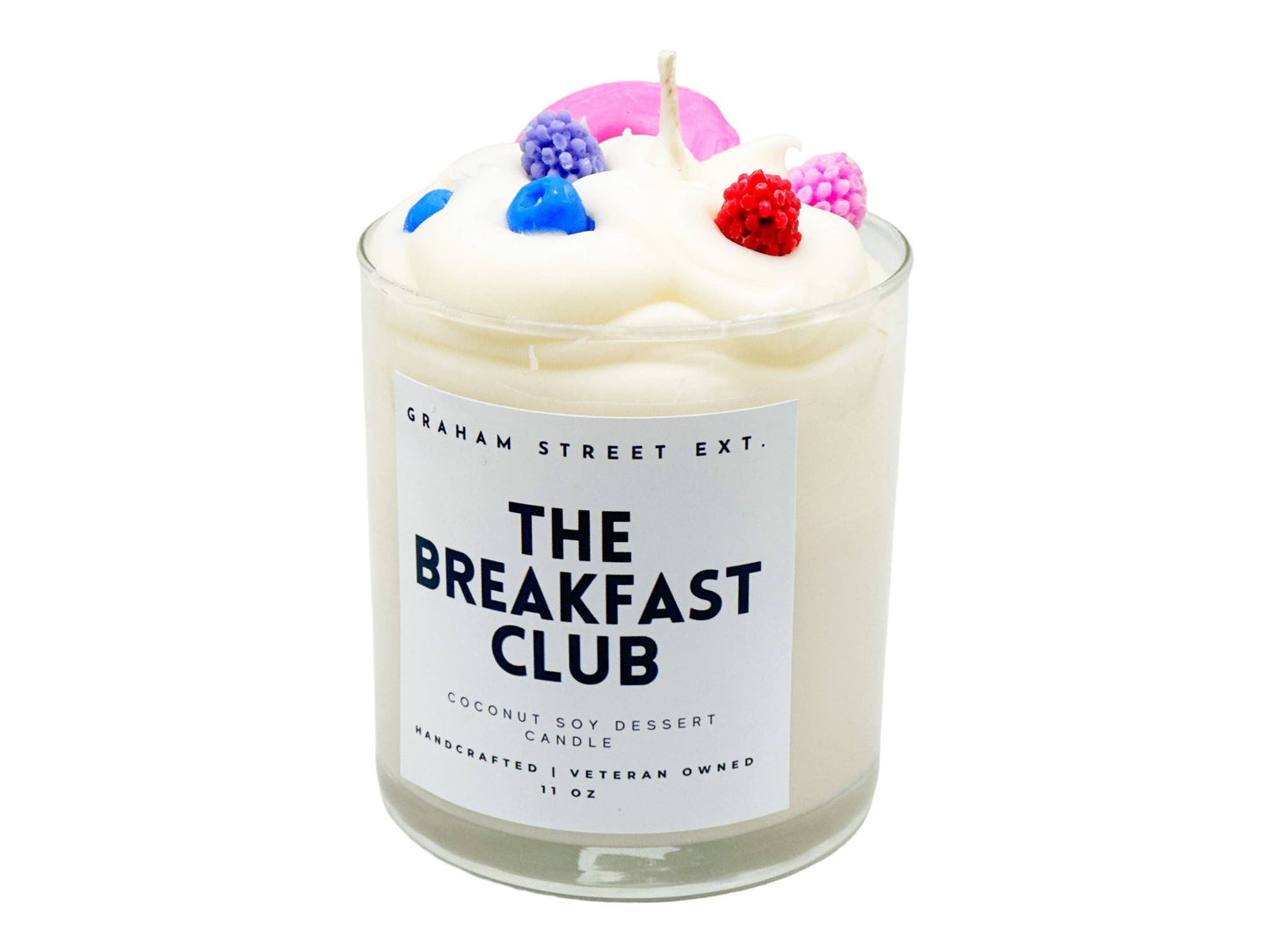 Handcrafted coconut soy dessert candle labeled 'The Breakfast Club' by Graham Street Ext. Features a whipped cream-like wax topping adorned with colorful faux berries and a pink accent, designed for a playful and unique aesthetic. 11 oz size, veteran-owned.