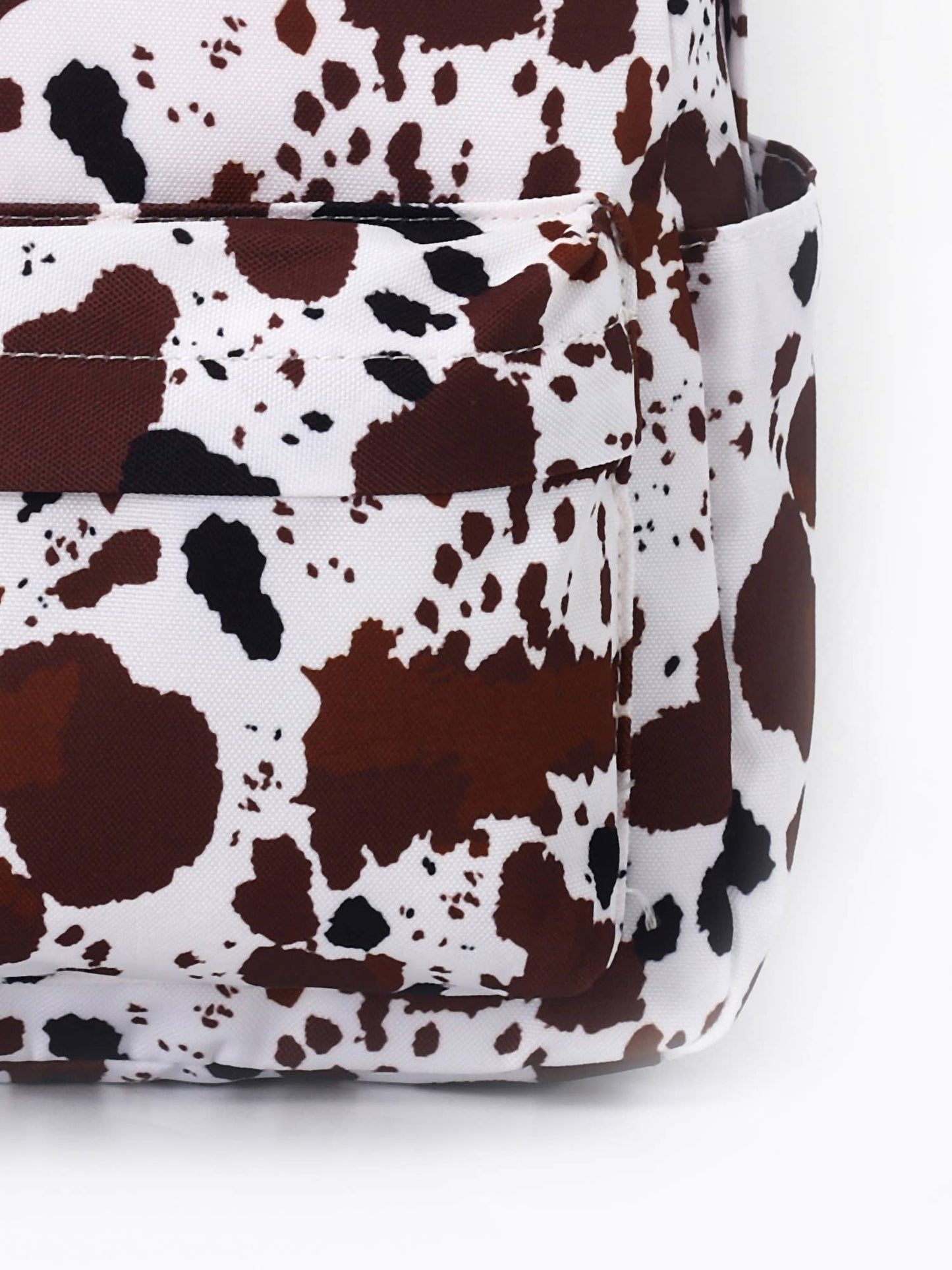 close up of the bold cow-print design, featuring a pattern of brown and black spots on a white background.