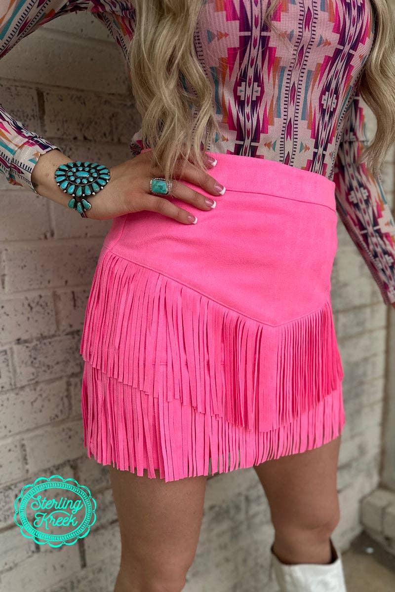 The pink western fringe skort offers a stylish and functional blend of contemporary fashion and western-inspired elements. The design features fringe detailing along the edges, providing movement and texture that enhances the overall aesthetic. The skort combines the look of a skirt with the practicality of built-in shorts, offering comfort and freedom of movement. The soft pink hue adds a feminine touch, while the western fringe accents elevate the piece with a trendy, boho flair.