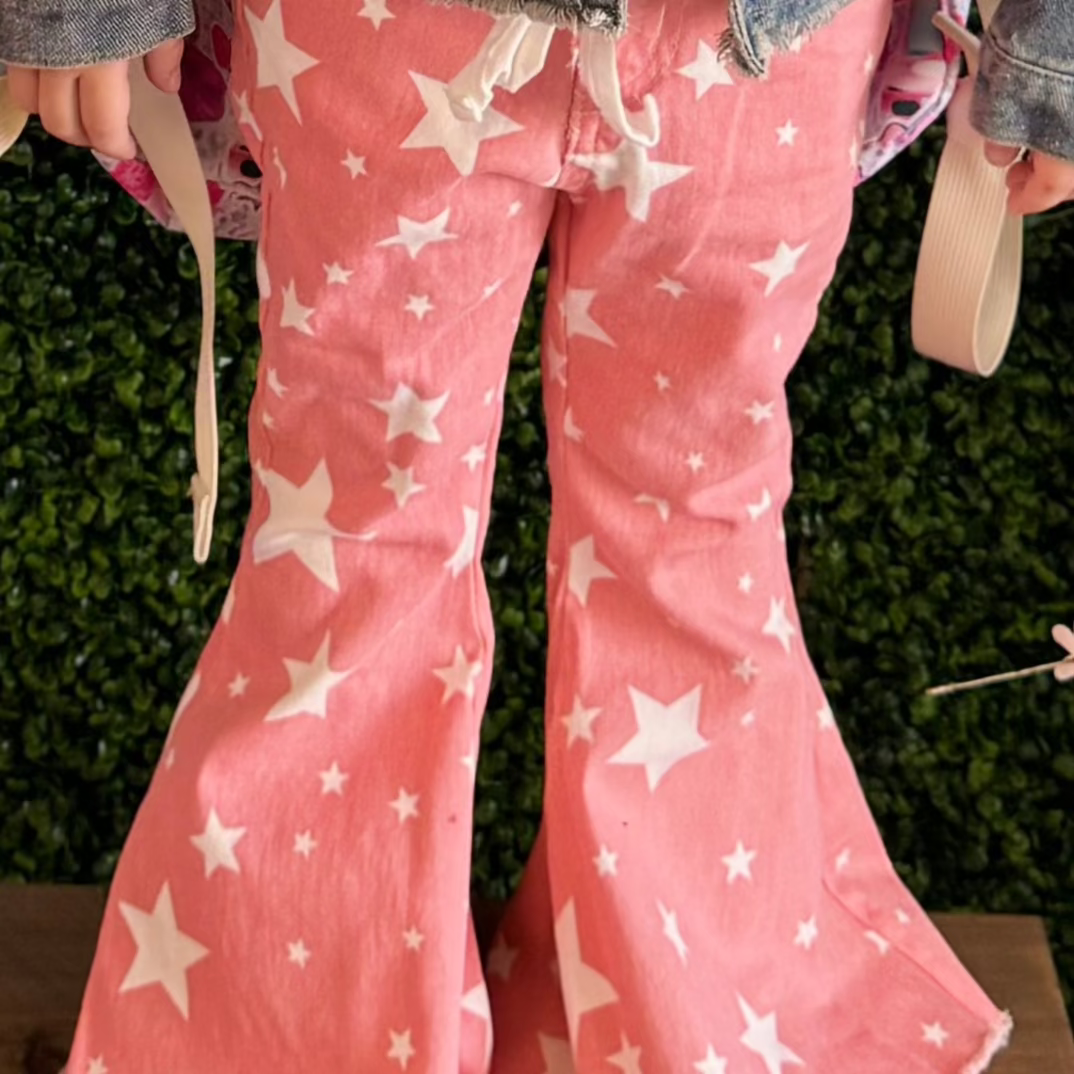 close up of the pink bell-bottom pants adorned with a bold white star pattern and frayed hems.