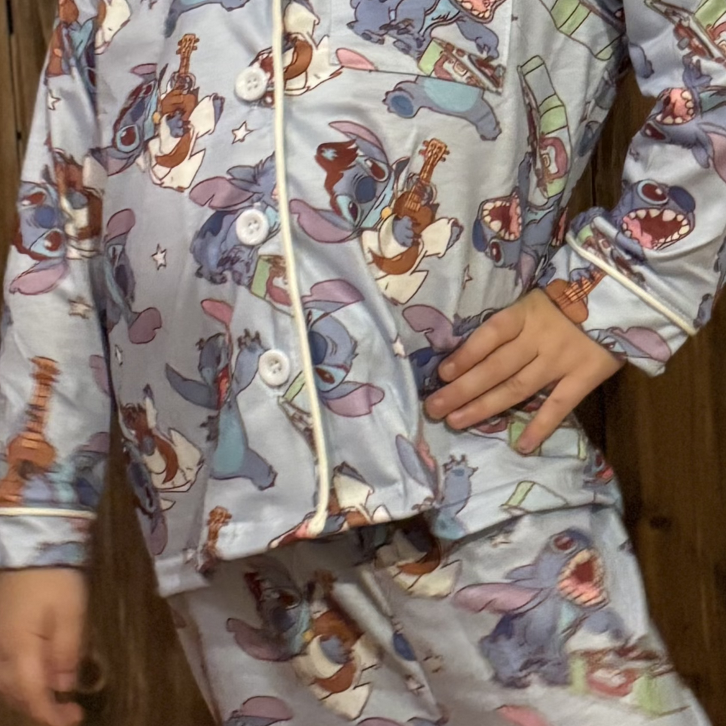 a close up of The long-sleeve button-up top and matching pants showcase vibrant colors and fun imagery, creating a cheerful bedtime look.