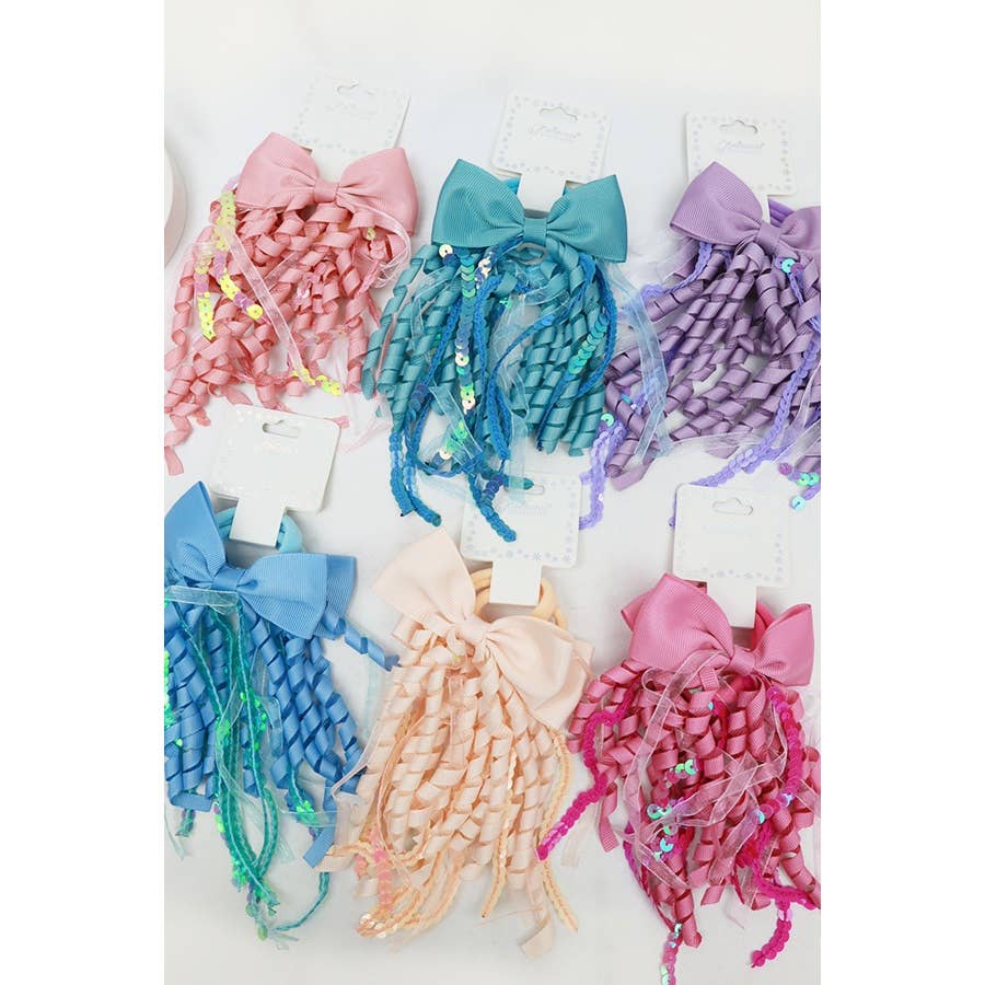 A collection of colorful hair accessories featuring large bows with cascading curly ribbons and decorative sequins. The bows are displayed in pastel and vibrant shades, including pink, blue, teal, purple, and peach, each attached to a display card on a white background.