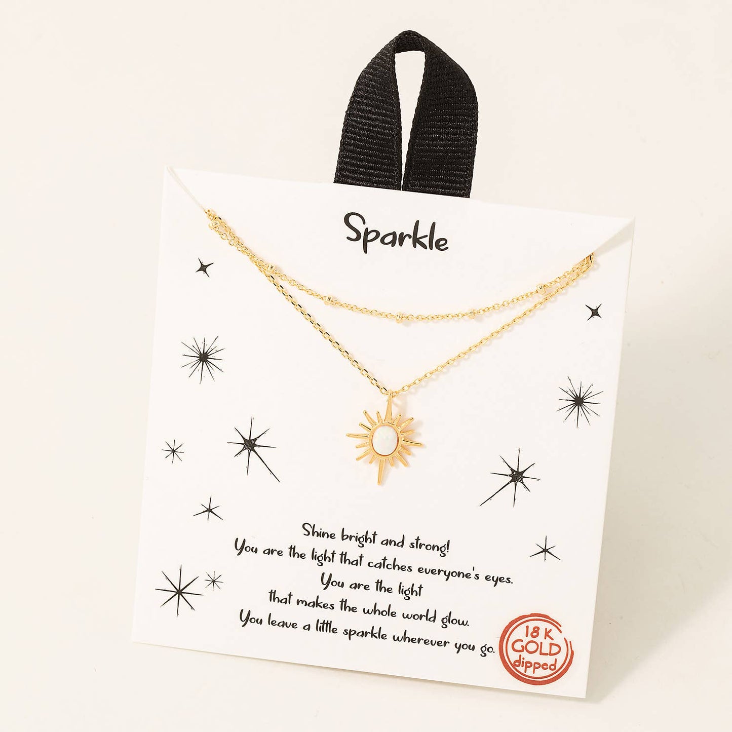 Gold double-layer necklace featuring a radiant sun pendant with a white opal center, displayed on a decorative card with the word 'Sparkle' at the top. The card includes an inspirational message and celestial star graphics, emphasizing the piece's uplifting and elegant design. Made with 18K gold plating, perfect for gifting or adding a luminous touch to any outfit.
