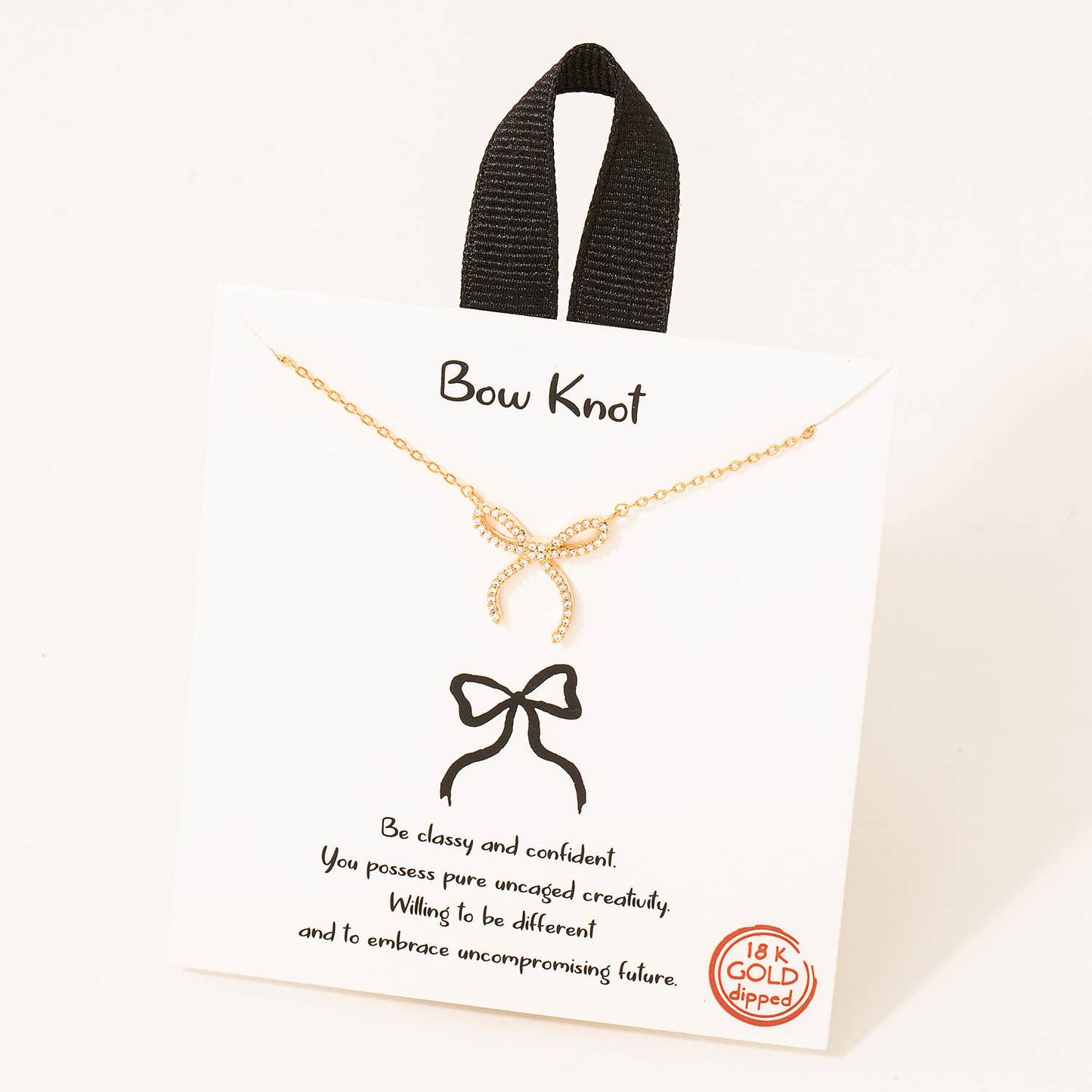 Delicate bow knot necklace available in white gold and 18k gold finishes, featuring a sleek chain with a dainty bow-shaped pendant adorned with shimmering crystals. Displayed on a stylish card with the phrase 'Be classy and confident,' making it a perfect gift for any occasion.