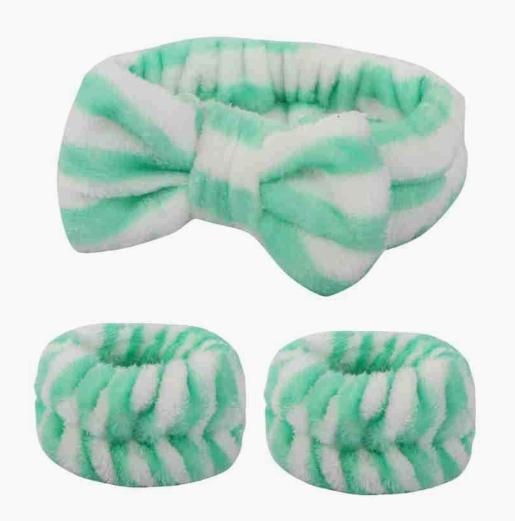 Green and white striped plush spa headband with a bow and matching wristbands, ideal for skincare or makeup application with a stylish, cozy design.