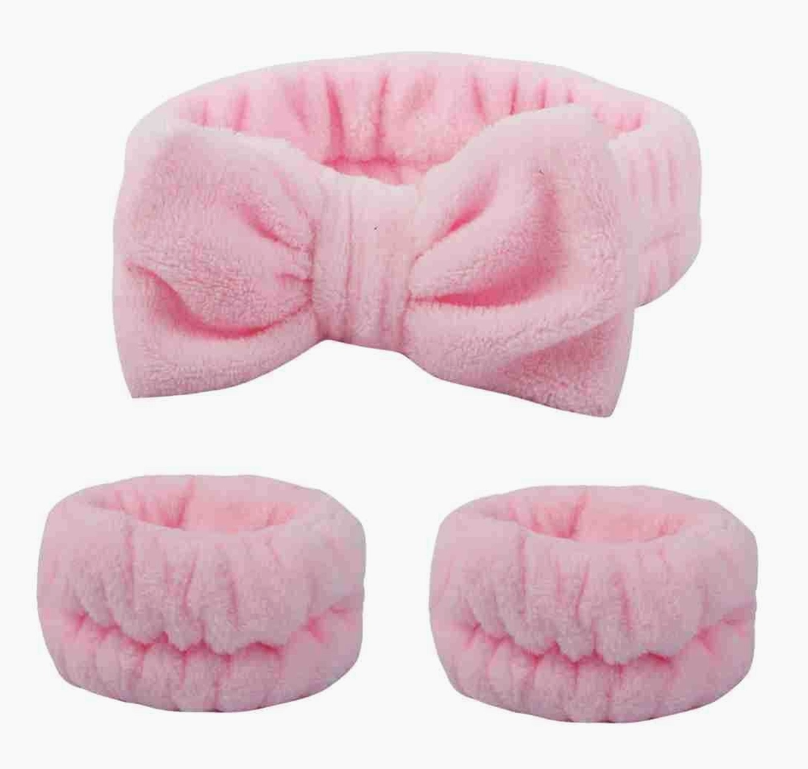 Pink plush spa headband featuring a bow design and matching wristbands, offering a cute and functional accessory set for self-care routines.