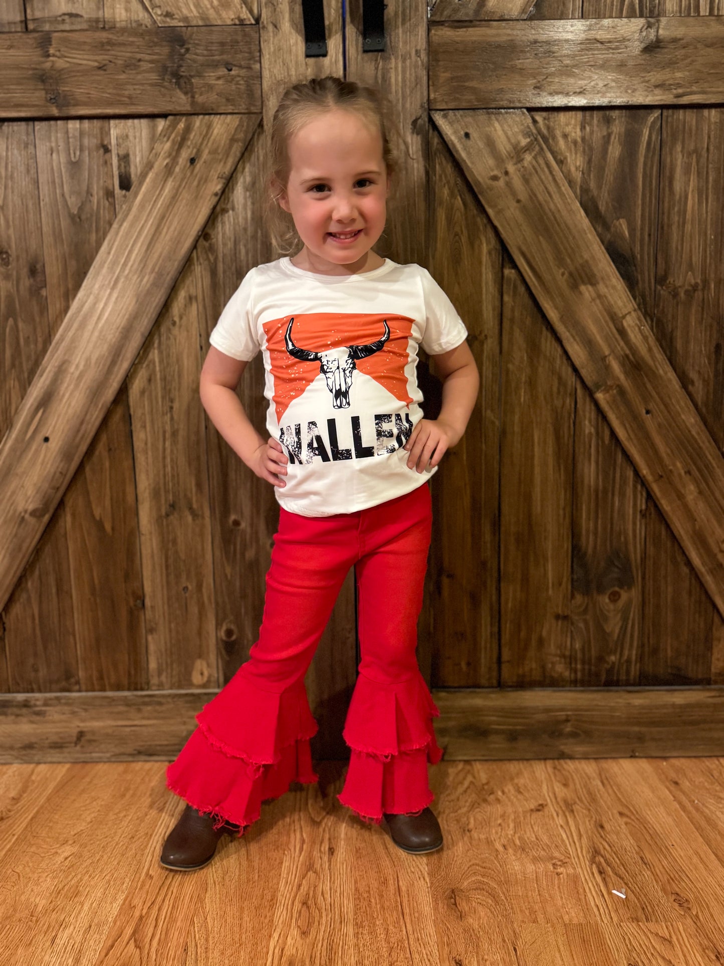 Rory modeling red double-layered bell-bottom jeans for kids, showcasing a bold and trendy flared design, paired with a confident pose, perfect for highlighting fashionable and comfortable children's clothing