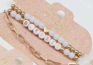Set of elegant bracelets featuring gold beads, white beads, and a white letter bead design spelling 'BLESSED.' The set includes a dainty gold heart accent and a stylish gold chain bracelet, displayed on a rustic beige backing card with a minimalist heart design, perfect for gifting or accessorizing with a positive touch.