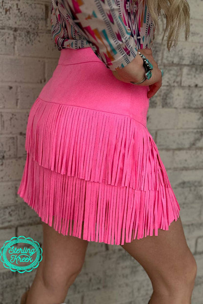 The pink western fringe skort offers a stylish and functional blend of contemporary fashion and western-inspired elements. The design features fringe detailing along the edges, providing movement and texture that enhances the overall aesthetic. The skort combines the look of a skirt with the practicality of built-in shorts, offering comfort and freedom of movement. The soft pink hue adds a feminine touch, while the western fringe accents elevate the piece with a trendy, boho flair.