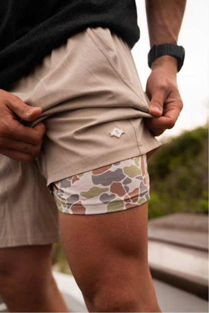 Tan Burlebo athletic shorts with Driftwood camo liner, stylish men's workout shorts, durable and comfortable activewear, camouflage-lined athletic shorts for outdoor sports, trendy Burlebo shorts with camo detail