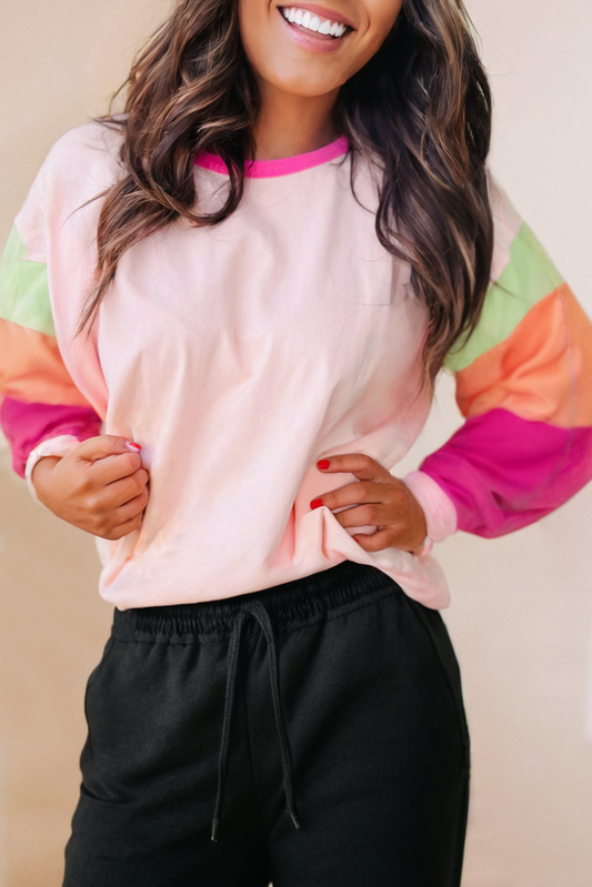Image of a long-sleeve blouse featuring a stylish color block design in various shades of pink, ranging from soft blush to vibrant fuchsia. The blouse has a relaxed yet tailored fit, with distinct blocks of color on the sleeves, body, and cuffs, creating a visually striking look. The different pink tones add dimension and flair, making this top perfect for adding a pop of color to any wardrobe. This color-blocked blouse is versatile, pairing well with jeans or skirts for a look that's both playful and chic.